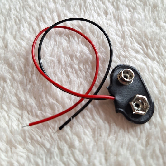 close up view of a black 9v battery connector, connected to approx 10cm of thin clack and red wire.