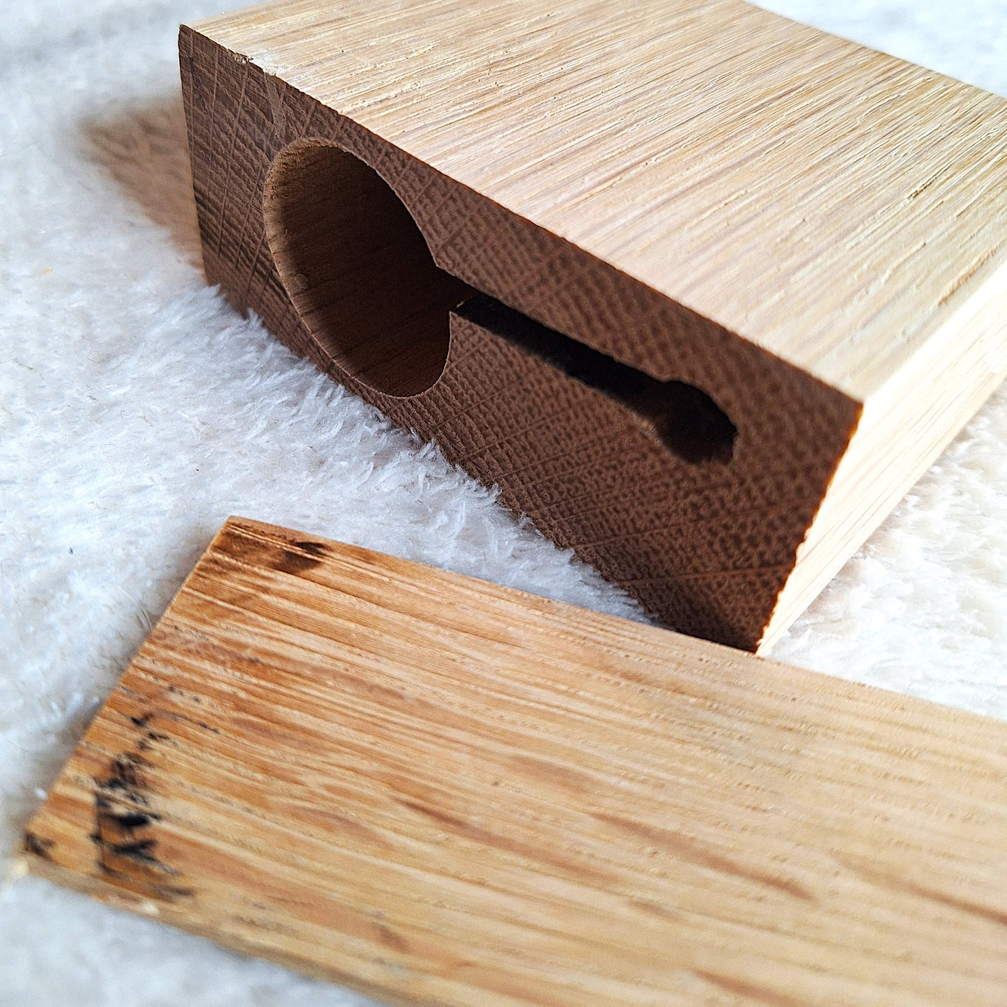 Rear oblique view of a solid oak stomp box enclosure cut to a wedge shape with an endplate, showing recesses for piezo pickup or microphone, ready to be used in a DIY build. On a white background.