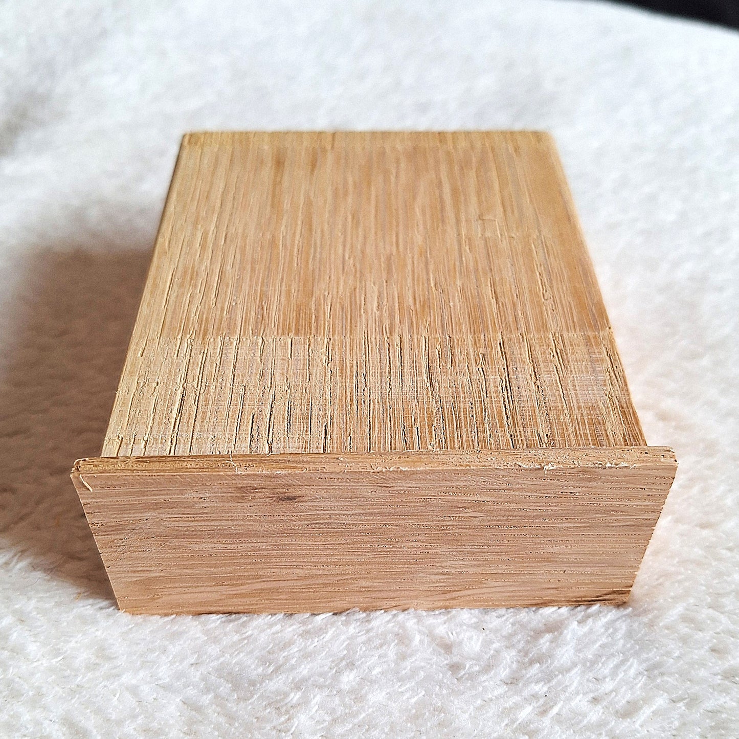 Top rear view of a solid oak stomp box enclosure and end plate ready to to be shaped and used in a home built project. On a white background.