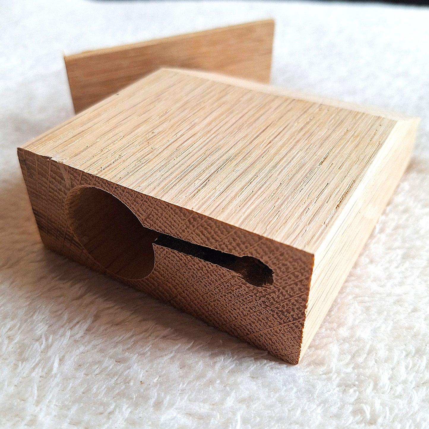 Rear view of a solid Oak stomp box enclosure cut to a wedge shape and showing recesses for a piezo pick-up or a microphone on a white background.