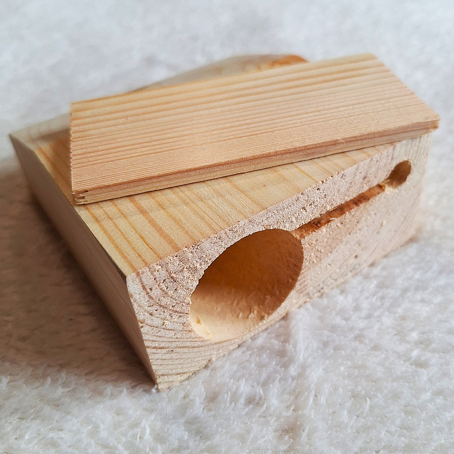 Rear view of a solid pine stomp box enclosure cut to a wedge shape and showing recesses for a piezo pick-up or a microphone on a white background.