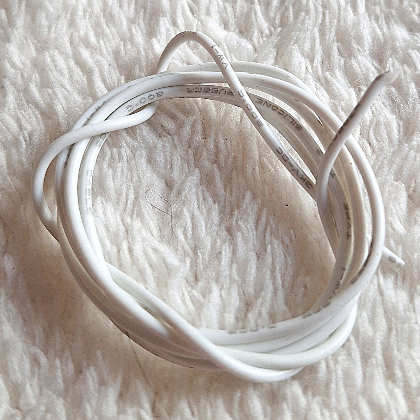 70cm of thin electrical wire, coiled and wrapped. on a white background