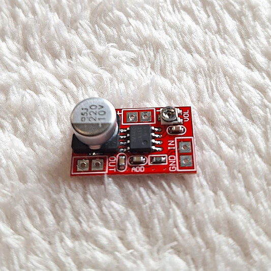 Close up of a red PCB mini preamplifier  featuring printed input and outputs. On a white surface.