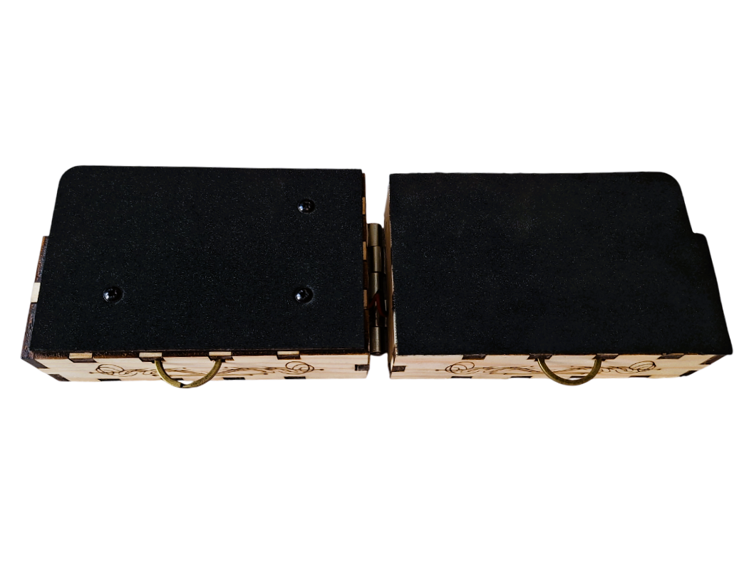 Opened front view of  'The Rhythmic' described as two laser-cut and etched pine boxes, both with a brass D-ring on the upper box edge, with one surface of each box covered in soft black neoprene foam, hinged with a metal connector and connected discretely with 2 wires. On a transparent background.