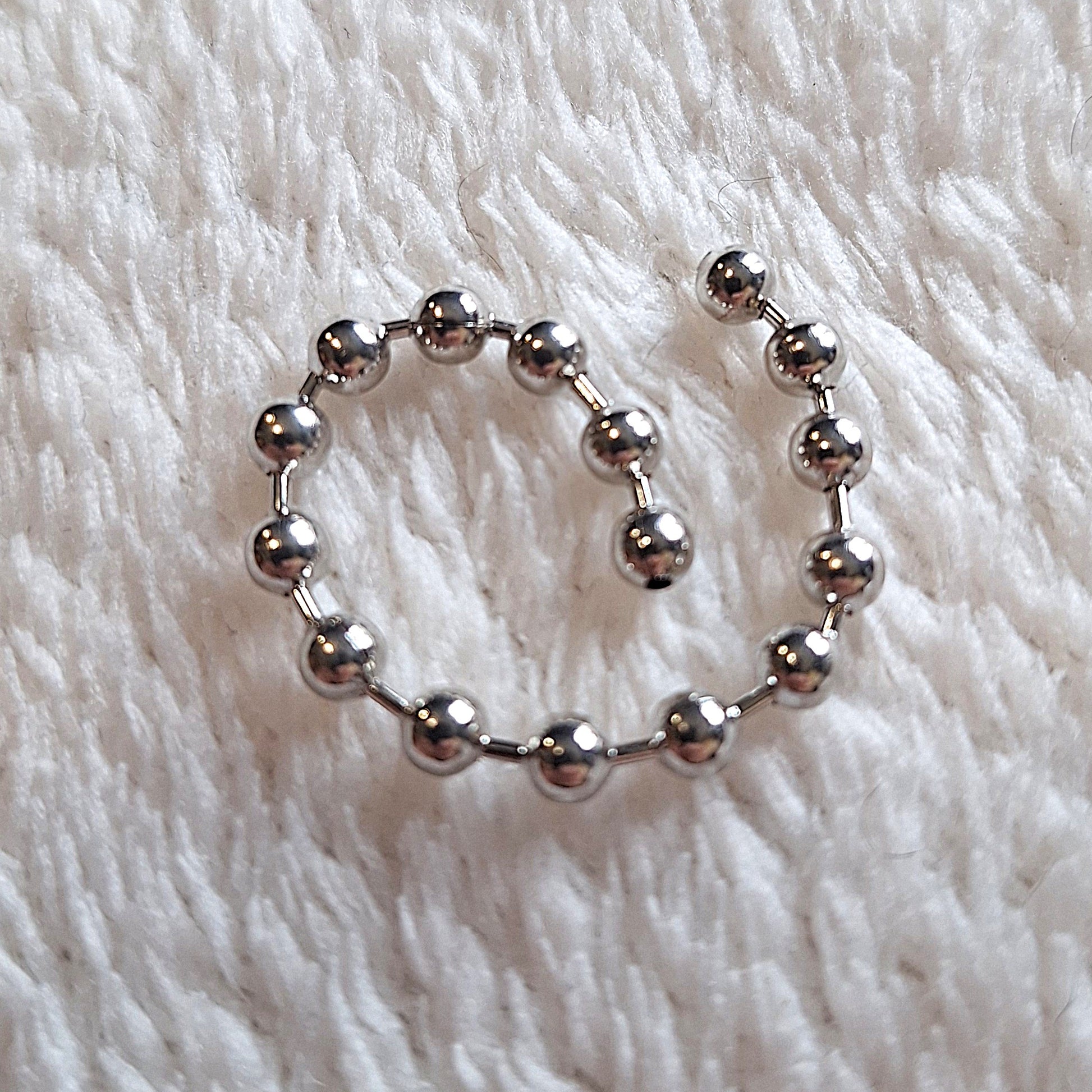 coiled 7cm length of linked metal beads on a white background