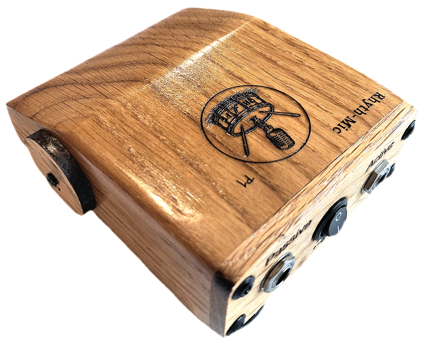 Rhyth-mic P1 play-through stompbox in solid oak wood showing laser etched branding of a microphone on a drum plus an on off switch, and passive and active input output 1/4 " jacks. Also shown is the circular oak 9v battery port cover