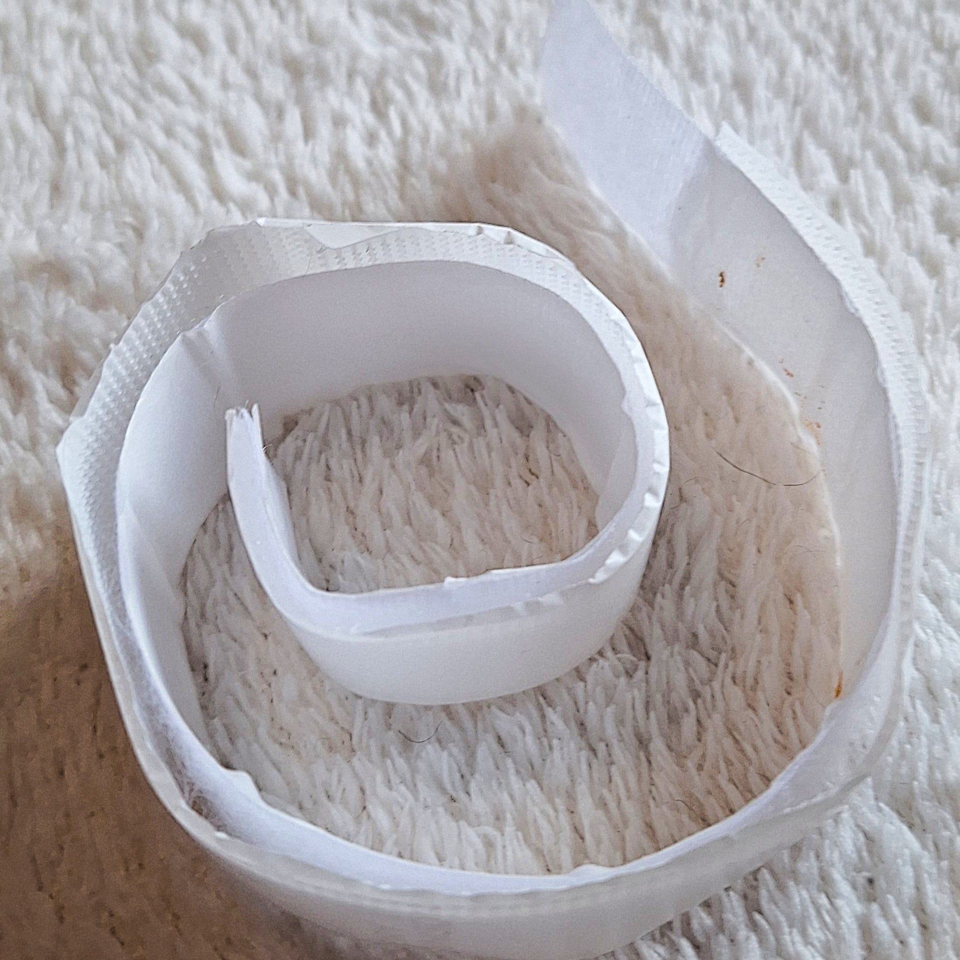 close up of a loosly coiled, white, 70cm length of velcro on a white background